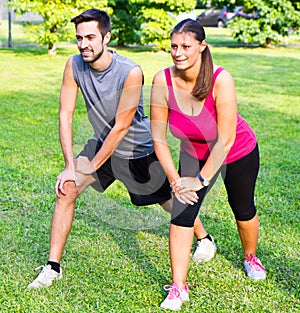 Smiling couple doing streching in the park photo