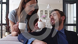 Smiling couple drinking tea at home together. Joyful couple taking coffee break