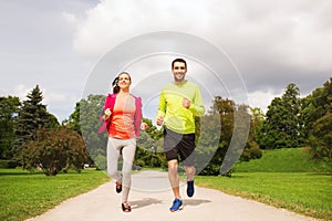 Smiling couple with earphones running outdoors