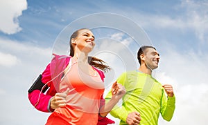 Smiling couple with earphones running outdoors