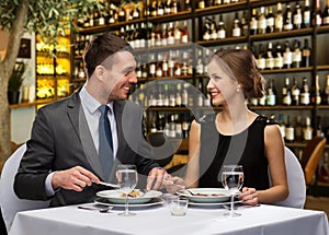 Smiling couple eating main course at restaurant