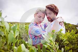 Smiling couple embracing outside among the bushes