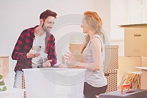 Smiling couple enjoying packing stuff while moving-into new home