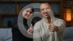 Smiling couple family african american man and arabian muslim woman diverse wife husband sitting on sofa together