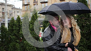 Smiling couple flirtation under the black umbrella when raining