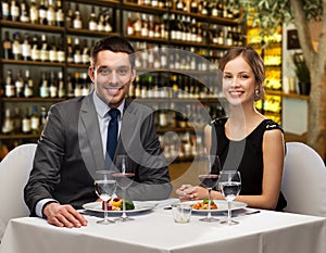 Smiling couple with food and wine at restaurant