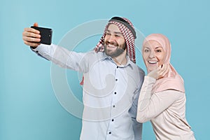 Smiling couple friends arabian muslim man wonam in keffiyeh kafiya ring igal agal hijab clothes isolated on blue