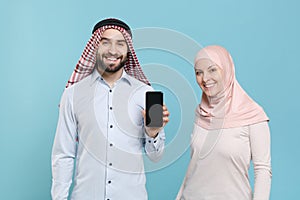 Smiling couple friends arabian muslim man wonam in keffiyeh kafiya ring igal agal hijab clothes isolated on blue photo