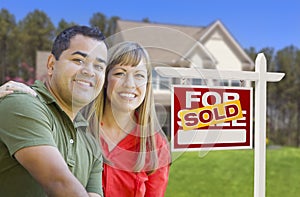 Smiling Couple in Front of Sold Real Estate Sign and House