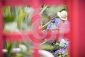 Smiling couple gardening seen through metallic structure