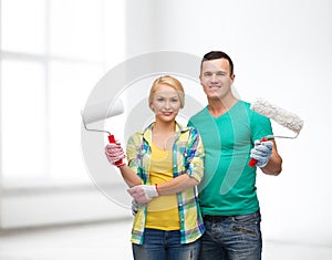 Smiling couple in gloves with paint rollers