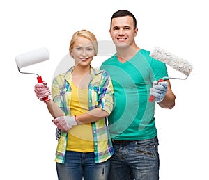 Smiling couple in gloves with paint rollers