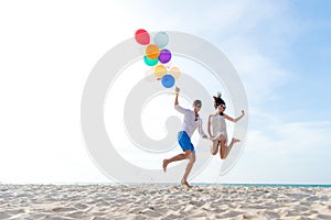 Smiling couple hand holding balloon and jumping together on the beach. Lover romantic and relax honeymoon in summer holiday. Summ