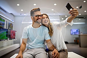 Smiling couple have fun using smartphone, watch video on cellphone make self-portrait picture