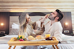 Couple having breakfast in bed in hotel room