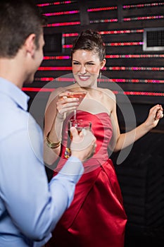 Smiling couple holding glass of beer and cocktail while dancing