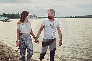 Smiling couple holding hands while walking on the beach