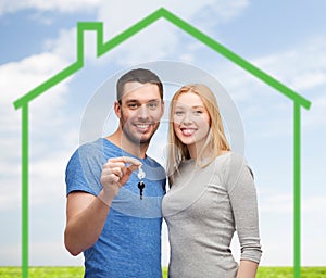 Smiling couple holding key over green house