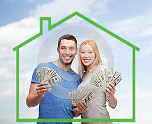 Smiling couple holding money over green house