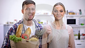 Smiling couple holding paper bag of groceries, healthy lifestyle, cooking