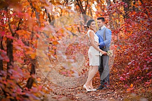 Smiling couple hugging in autumn park. Happy bride and groom in forest, outdoors