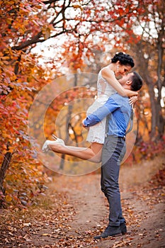 Smiling couple hugging in autumn park. Happy bride and groom in forest, outdoors