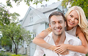 Smiling couple hugging over house background