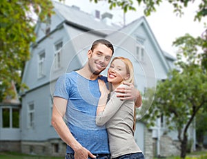 Smiling couple hugging over house background