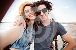 Smiling couple hugging and taking selfie on the beach