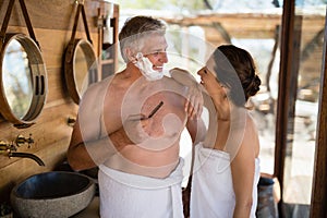 Smiling couple interacting while shaving in cottage