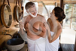 Smiling couple interacting while shaving in cottage