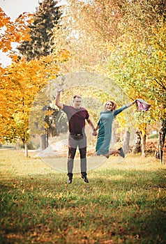 Smiling couple jumping in autumn park