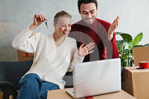 Smiling couple with laptop sitting on floor