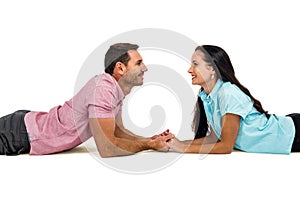 Smiling couple laying on the floor face to face holding hands