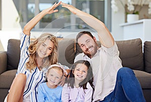 Smiling couple with little kids sitting and making symbolic roof with hands over children. Cheerful family sitting