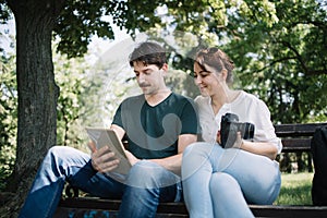 Smiling couple looking at tablet while sitting on bench outdoor