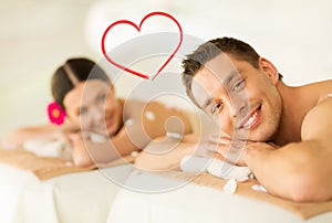 Smiling couple lying on massage table in spa salon