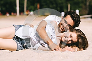 smiling couple lying on sandy city beach and looking