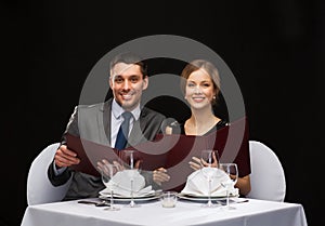 Smiling couple with menus at restaurant