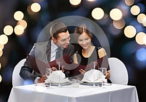 Smiling couple with menus at restaurant