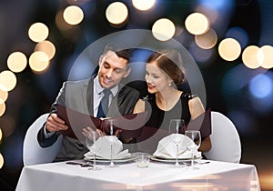 Smiling couple with menus at restaurant