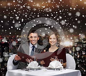 Smiling couple with menus at restaurant