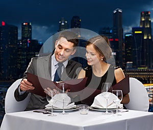 Smiling couple with menus at restaurant