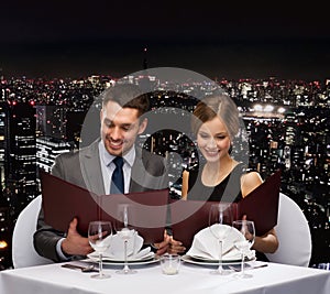 Smiling couple with menus at restaurant