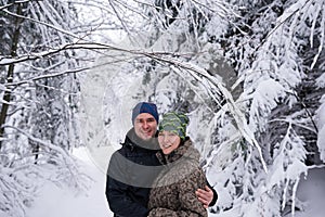 Smiling couple out hiking together in a snow covered forest