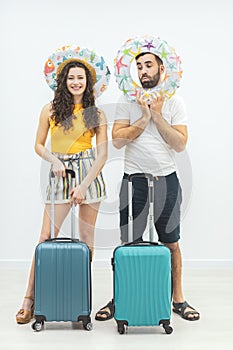 Smiling couple with passports and suitcases on a white background.