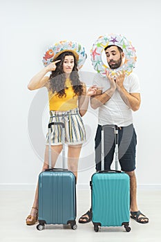 Smiling couple with passports and suitcases on a white background.