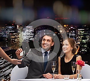Smiling couple paying for dinner with credit card
