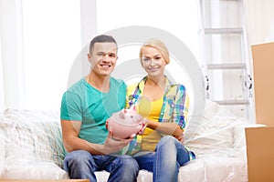 Smiling couple with piggybank in new home