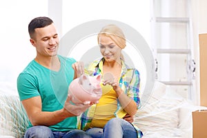 Smiling couple with piggybank in new home